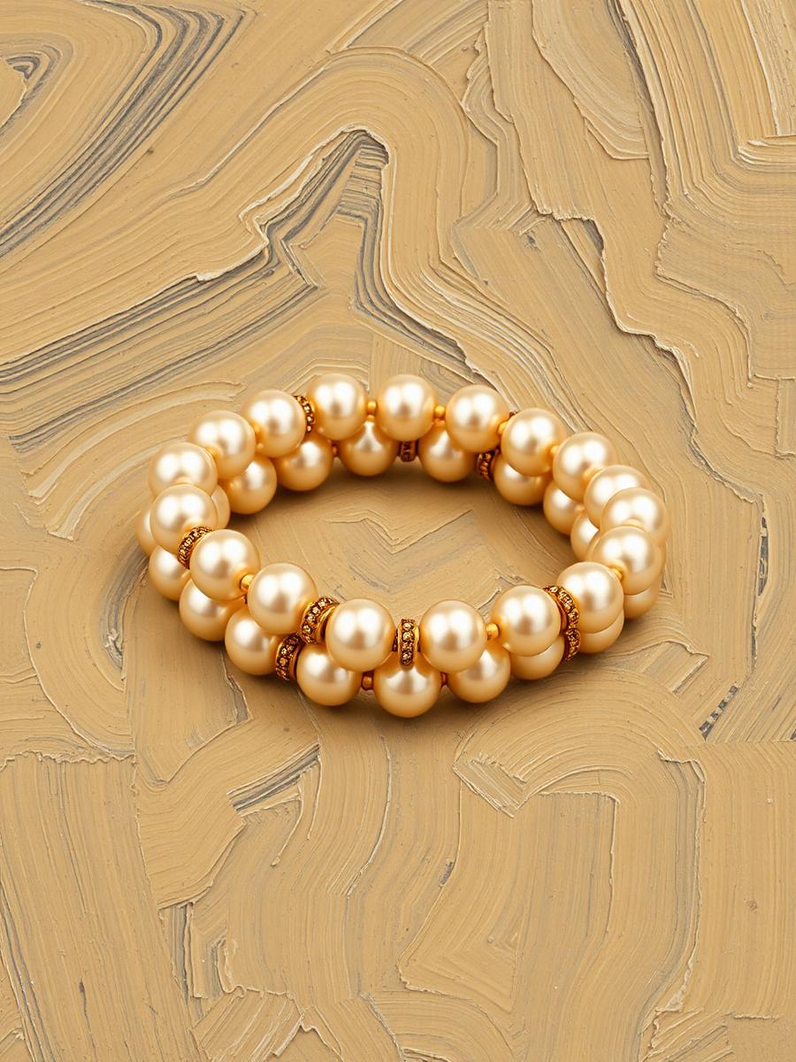 Pulseira dourada com pérolas e zircônias sobre pedra escura